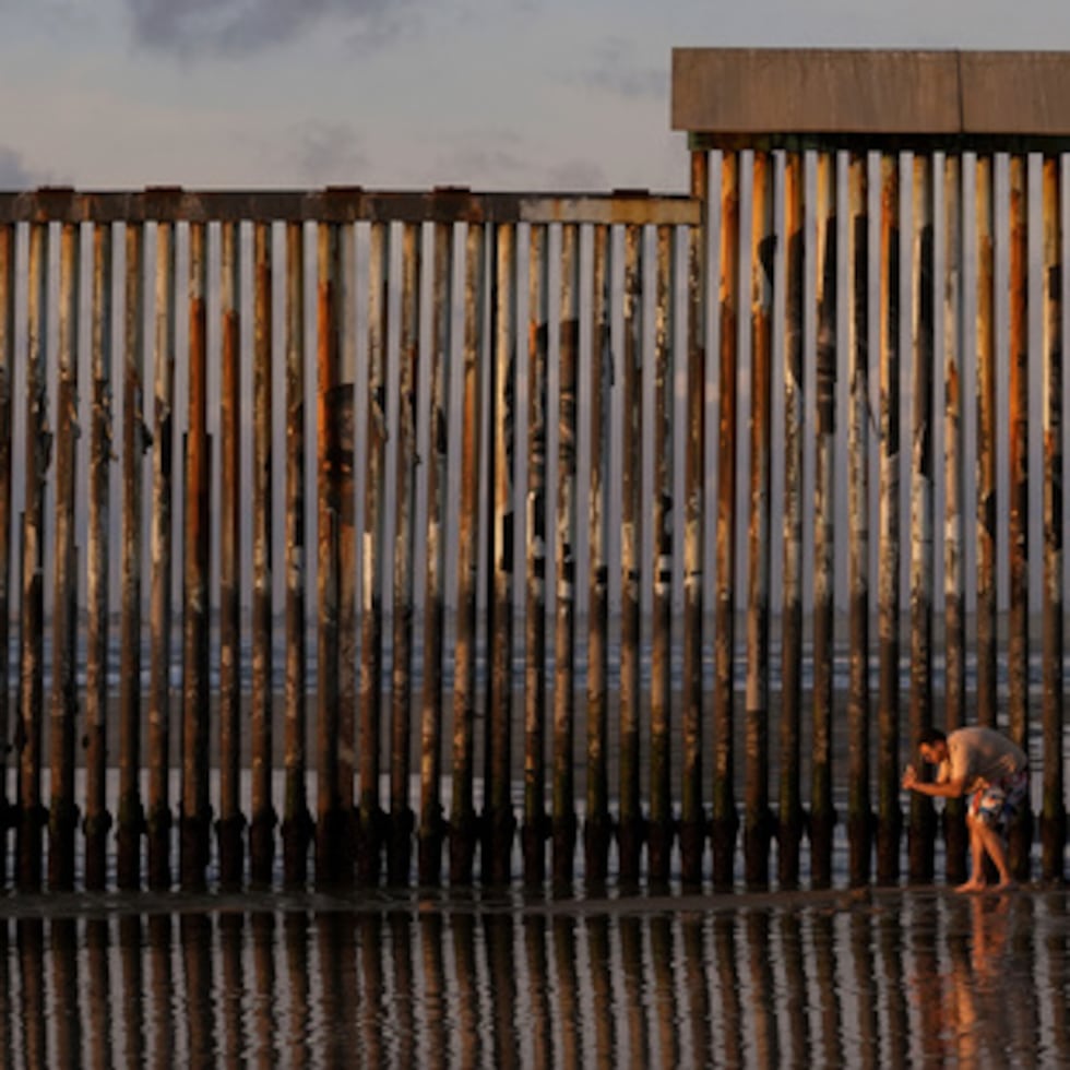 Un hombre toma una imagen con su teléfono junto al lugar donde el muro fronterizo que separa México de Estados Unidos llega hasta el océano Pacífico el 28 de enero de 2025, en Tijuana, México. (AP Photo/Gregory Bull, Archivo)