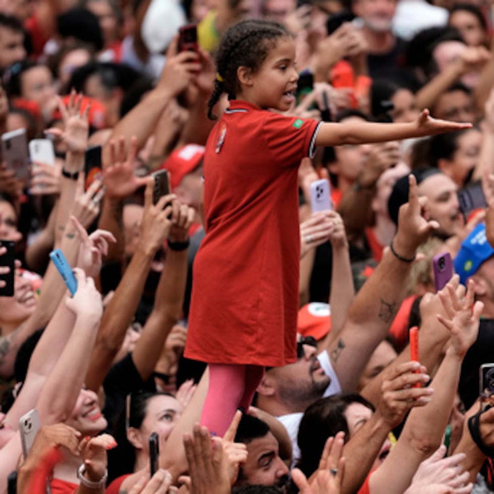 Una niña, de pie sobre los hombros de un hombre, extiende la mano en medio de una multitud de seguidores del presidente brasileño Luiz Inácio Lula da Silva, que se presenta a la reelección, durante su último mitin de campaña, un día antes de la segunda vuelta de las elecciones presidenciales en São Paulo.