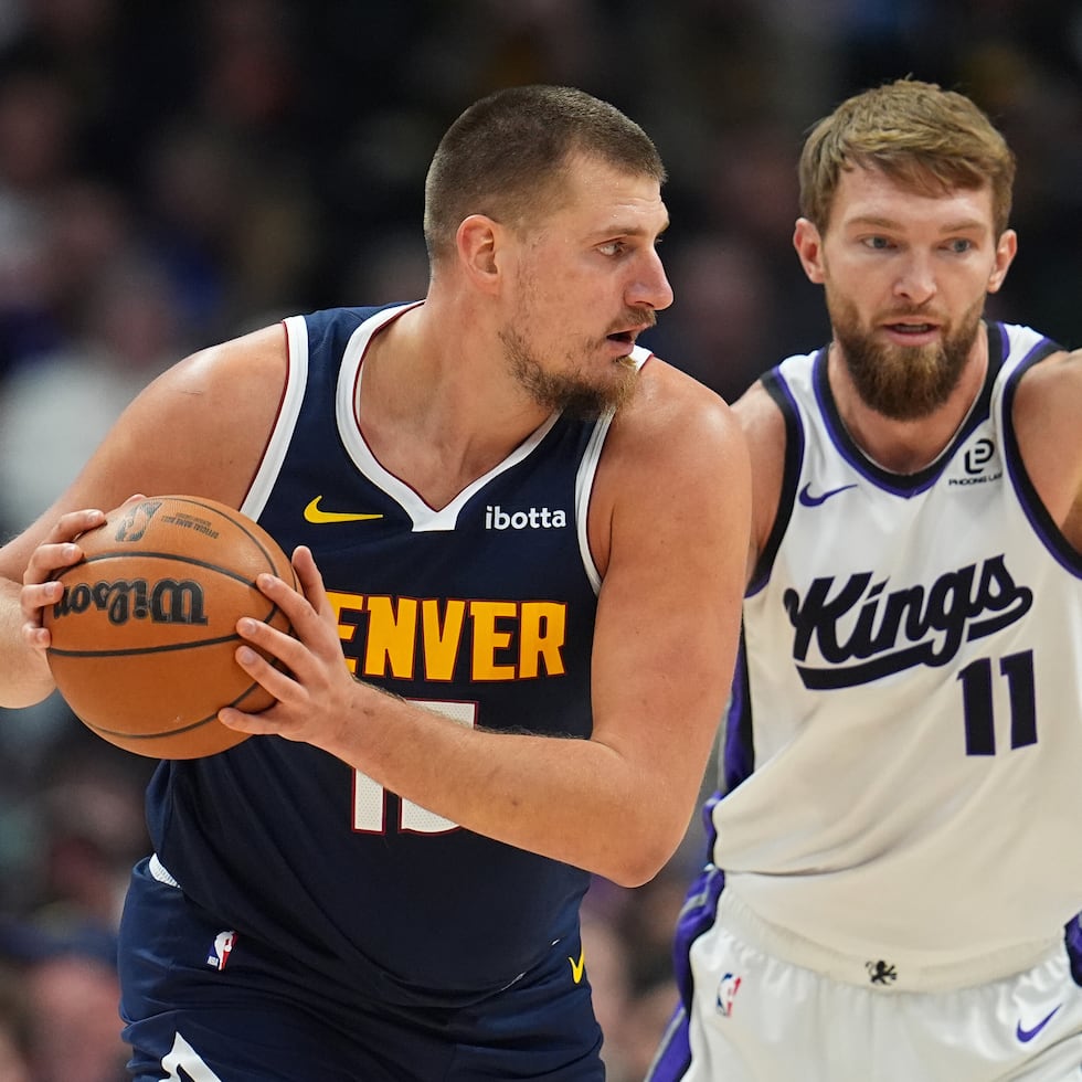 Nikola Jokic, izquierda, de los Nuggets de Denver, busca pasar el balón mientras Domantas Sabonis, de los Kings de Sacramento, lo defiende.