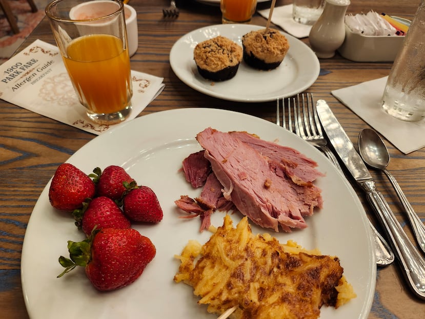 Desayuno que contiene alimentos libres de gluten como fresas, jamón, cazuela de papas y magdalenas.