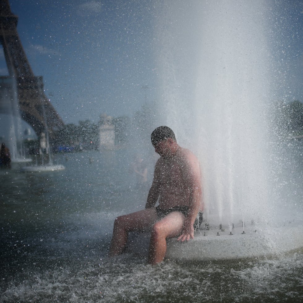 Una persona se refresca en una fuente en el Trocadero, cerca de la Torre Eiffel, durante una ola de calor, en París.
