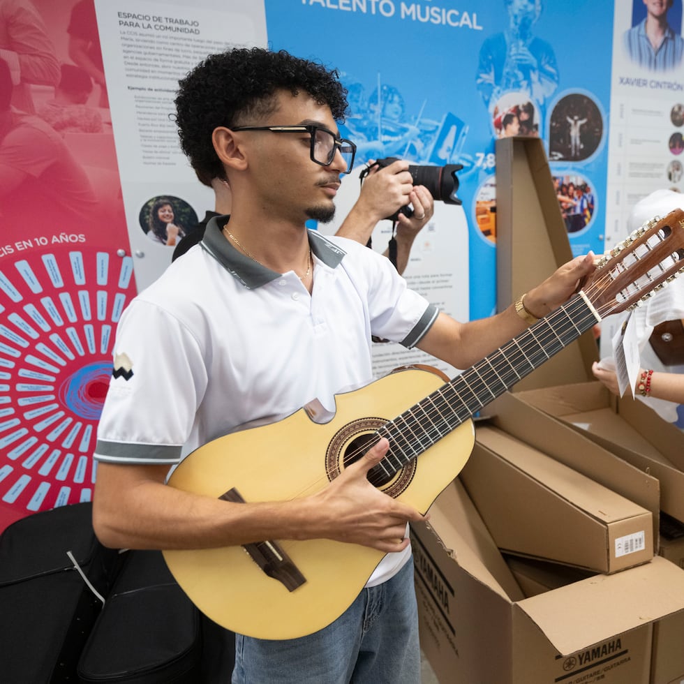 Un estudiante de la Escuela de Bellas Artes José Ignacio Quintón de Coamo revisa un cuatro puertorriqueño que fue donado a la escuela, como parte del programa "Revive la música".