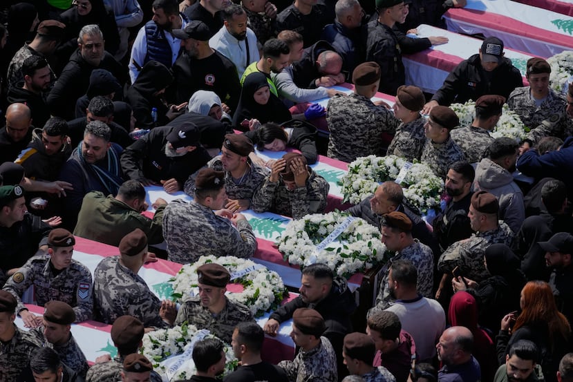 Colleagues mourn over the coffins during the funeral of 13 state security officers killed the previous day in an Israeli strike in the Lebanese coastal city of Sidon, Saturday, April 11, 2026. (AP Photo/Mohammed Zaatari)