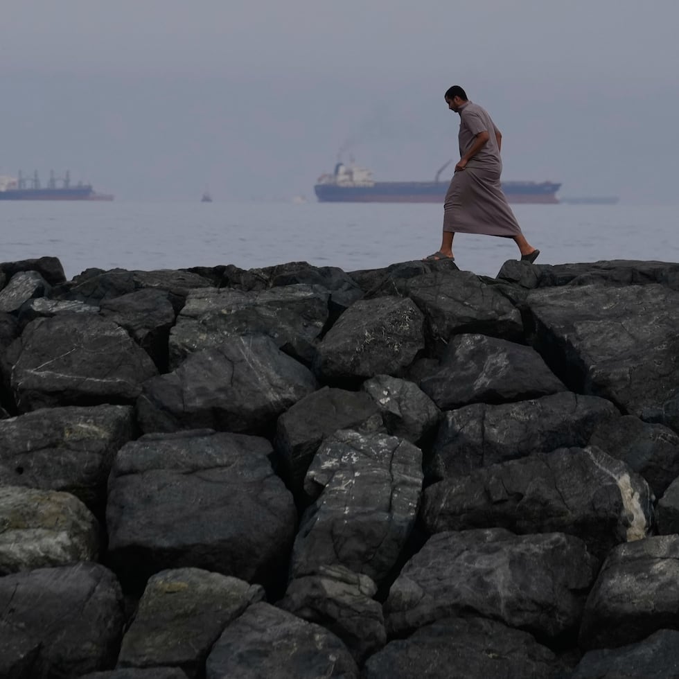 Un hombre camina por la orilla mientras buques petroleros y cargueros se alinean en el estrecho de Ormuz, visto desde Khor Fakkan, Emiratos Árabes Unidos, 11 de marzo de 2026. 