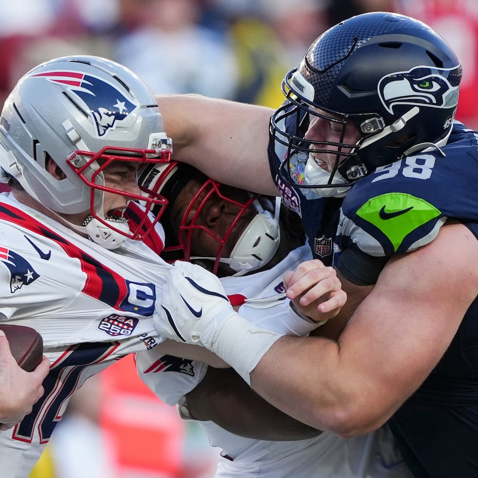 El jugador defensivo de los Seahawks, Rylie Mills, derriba al quarterback de los Patriots, Drake Maye.