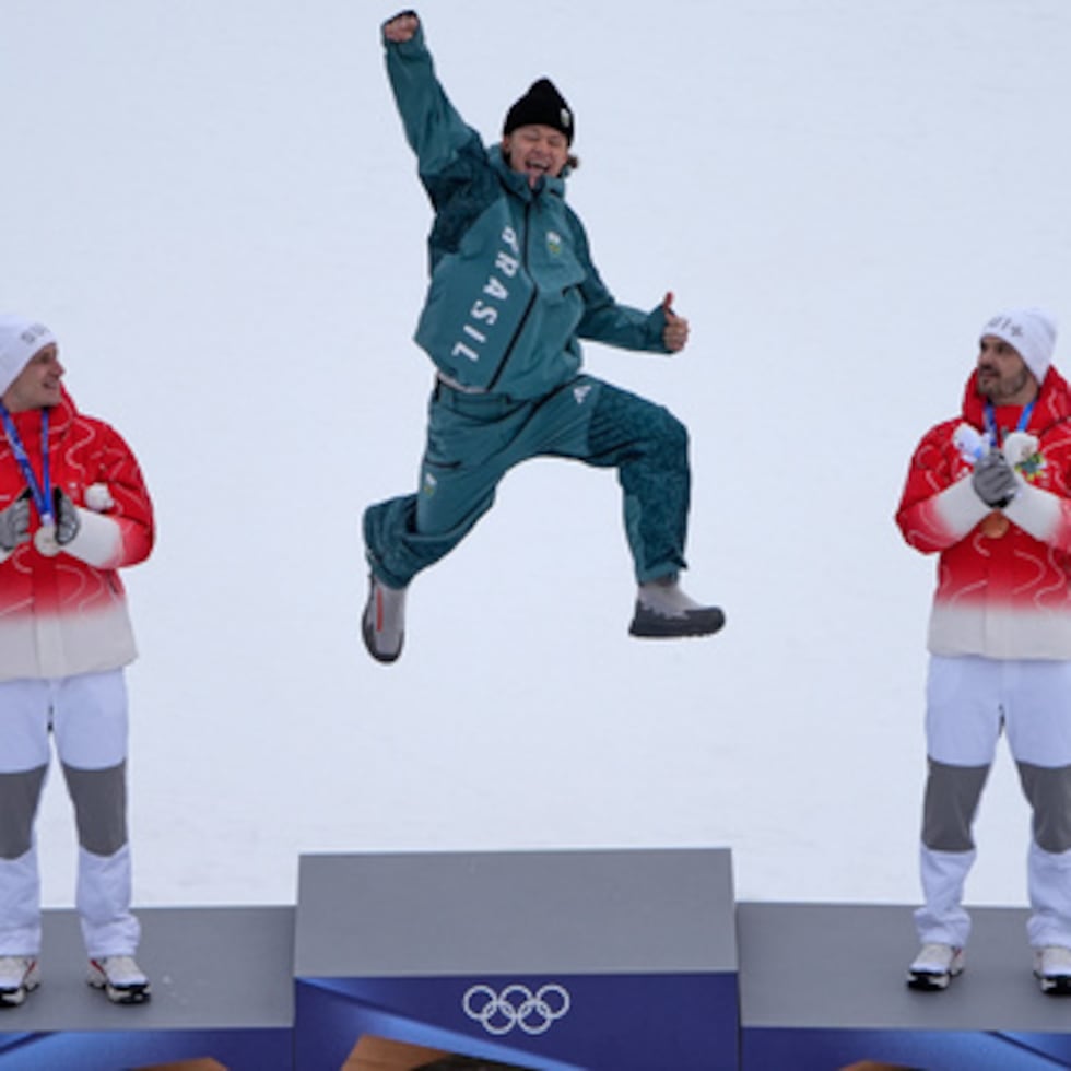 El brasileño Lucas Pinheiro Braathen, en el centro, ganador de la prueba de eslalon gigante masculino de esquí alpino, salta en señal de celebración en el podio, flanqueado por el suizo Marco Odermatt, a la izquierda, segundo clasificado, y el suizo Loic Meillard, tercero, en los Juegos Olímpicos de Invierno de 2026, en Bormio, Italia.