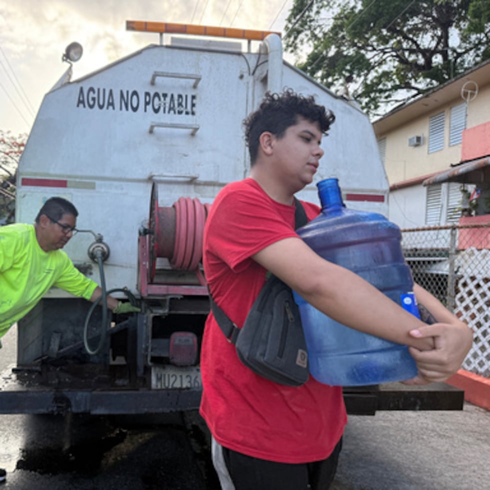 Bryan Pérez lleva un bidón de agua de 19 litros a su apartamento en el complejo de viviendas sociales Villa Kennedy, en San Juan (Puerto Rico), el miércoles 10 de junio de 2026. (Foto AP/Danica Coto)