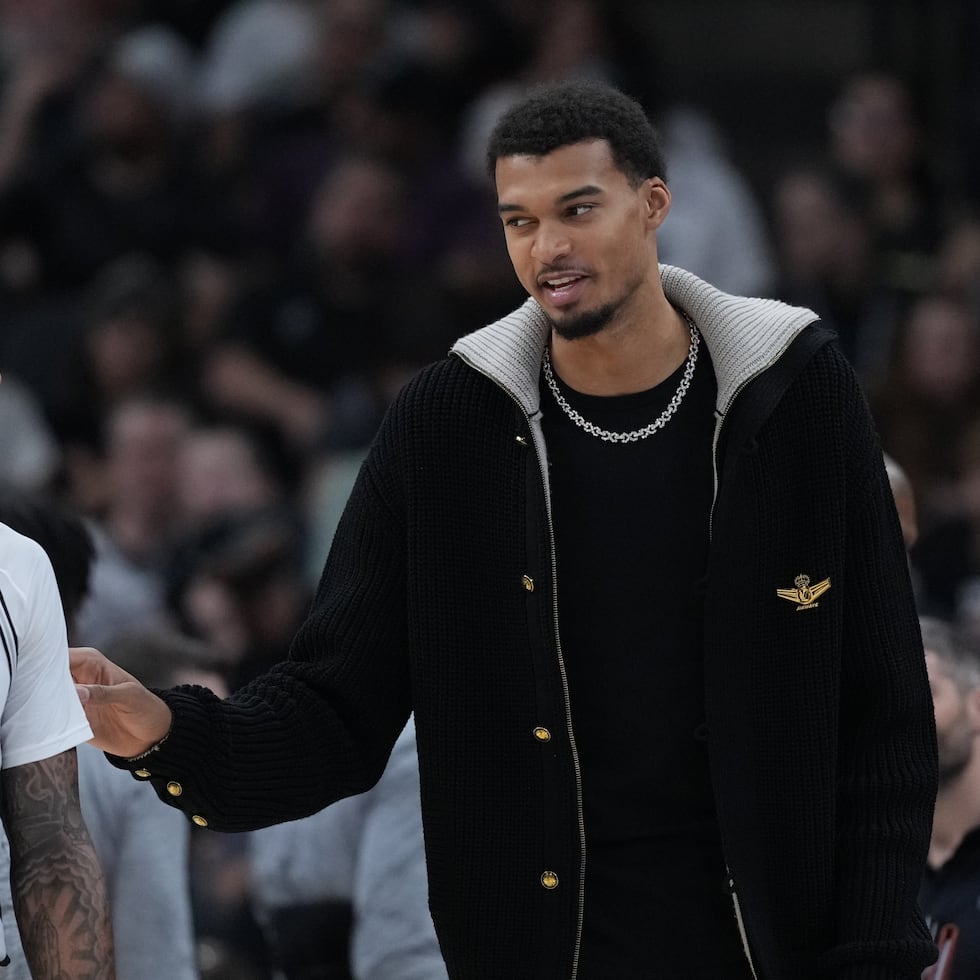 Victor Wembanyama, alero de los Spurs de San Antonio, a la derecha, habla con su compañero de equipo, el alero Julian Champagnie (30), durante la primera mitad de un juego contra los Kings de Sacramento en San Antonio.