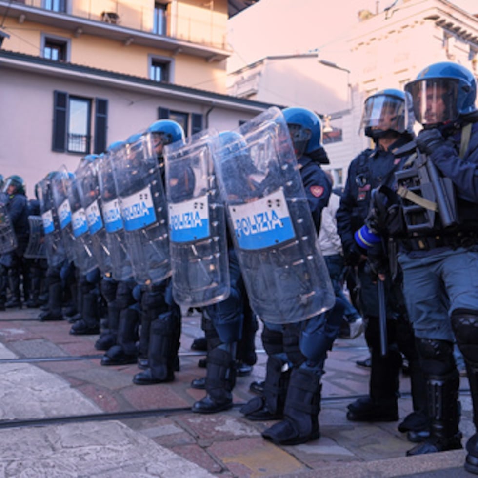 La policía antidisturbios observa cómo los manifestantes desfilan por las calles de Milán, Italia, el sábado 24 de octubre, para protestar contra el aumento del costo de la vida y el deterioro de los servicios público.