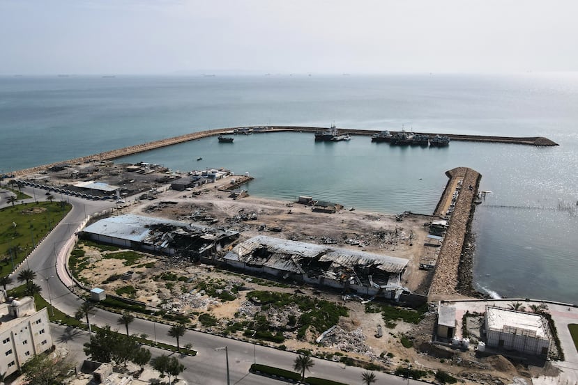 Con barcos en el estrecho de Ormuz como telón de fondo, se aprecian los daños, según testigos locales, causados por varios ataques aéreos recientes durante la campaña militar entre Estados Unidos e Israel, en un muelle pesquero del puerto de la isla de Qeshm, Irán, el lunes 13 de abril de 2026. (Foto AP/Asghar Besharati)