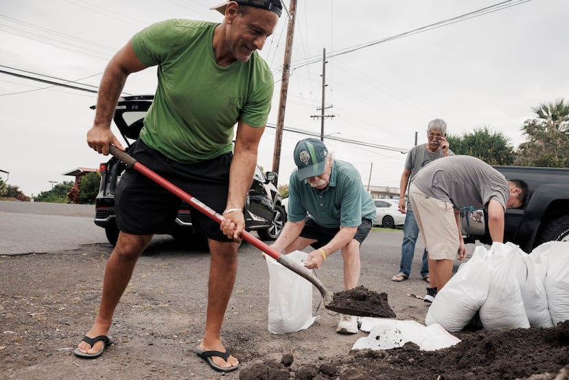 Shaheer Faltas, a la izquierda, y su suegro, Joe Brosnan, llenan sacos de arena en preparación para la llegada de la tormenta tropical Lala en Captain Cook, Hawái, el viernes 14 de agosto de 2026. (Stephen Lam/San Francisco Chronicle vía AP)