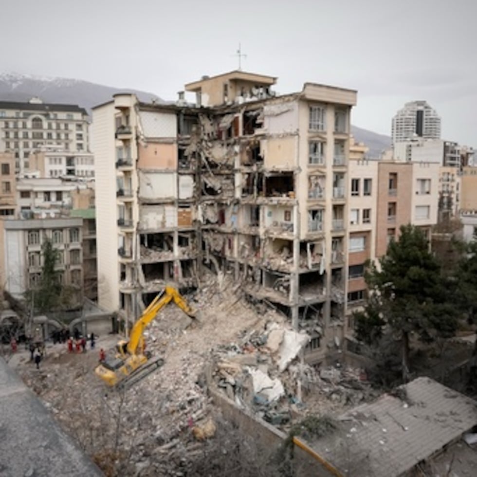 Trabajadores de emergencia de la Media Luna Roja iraní utilizan una excavadora para retirar los escombros de un edificio residencial que fue alcanzado en un ataque estadounidense-israelí en Teherán, Irán.