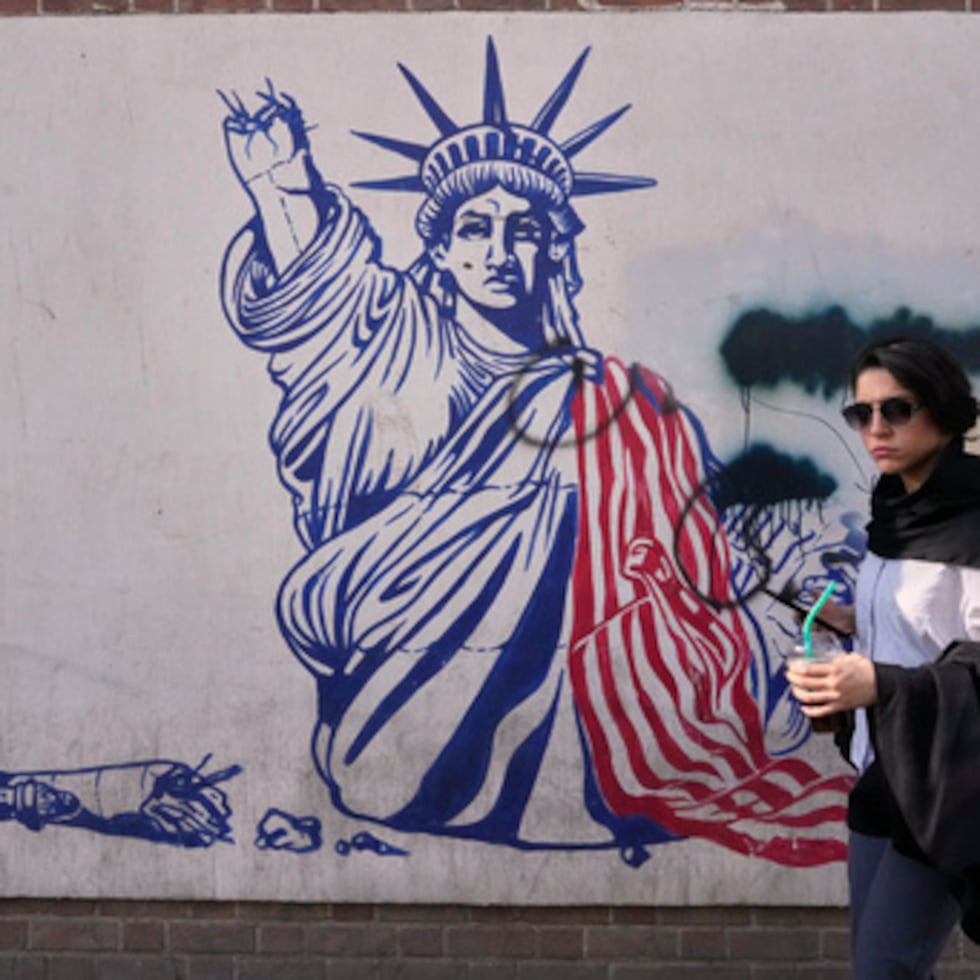 Una mujer pasa junto a un mural antiestadounidense en la pared de la antigua embajada de Estados Unidos, ahora convertida en museo, en Teherán.