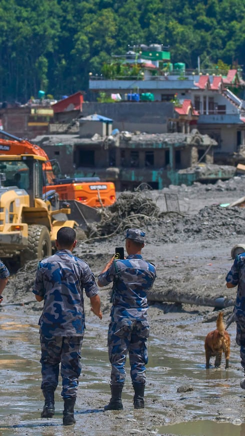 Policías nepalíes observan el jueves cómo excavadoras retiran los escombros de las inundaciones repentinas en el distrito de Nuwakot, Nepal.