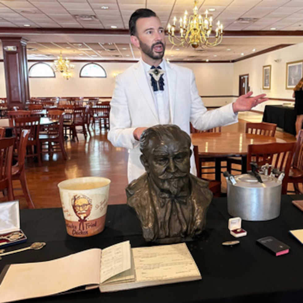 El subastador Jonathan Klunk muestra una serie de objetos personales de Harland Sanders, fundador de KFC, el miércoles 22 de julio de 2026, en Shelbyville, Kentucky. (Foto AP/Dylan Lovan)