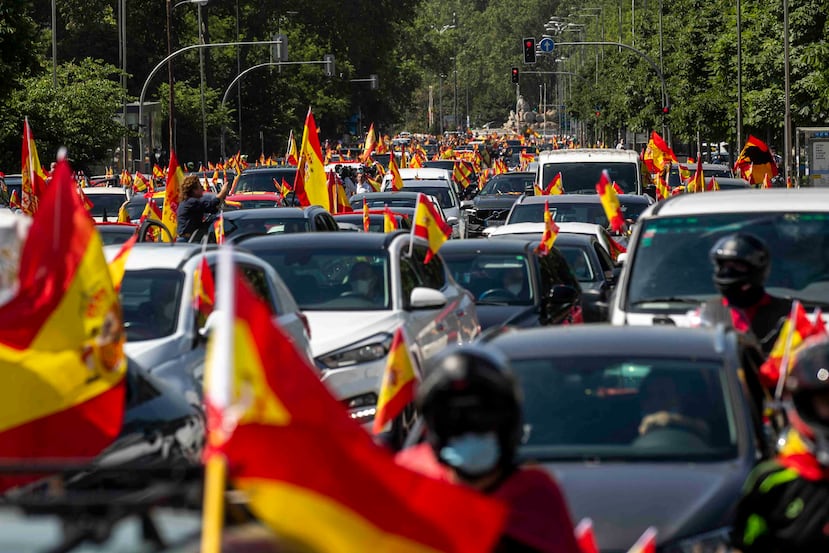 Personas ondean la bandera de España durante una protesta organizada por el partido Vox de extrema derecha contra el manejo del gobierno español durante la pandemia. )AP)