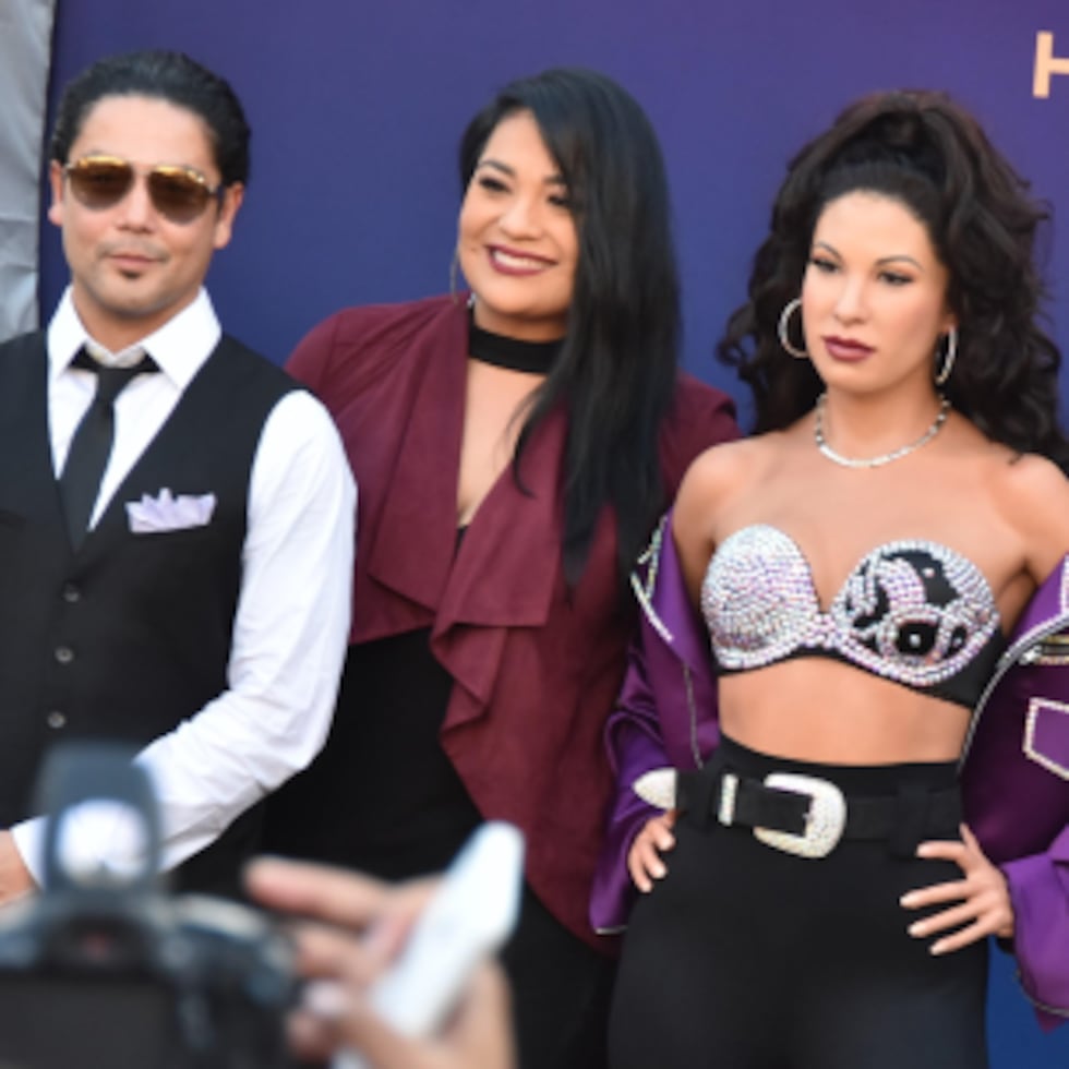 Los hermanos de Selena, A.B. y Suzette Quintanilla; y su viudo, Chris Pérez; posan con la figura. (Prensa Asociada)
