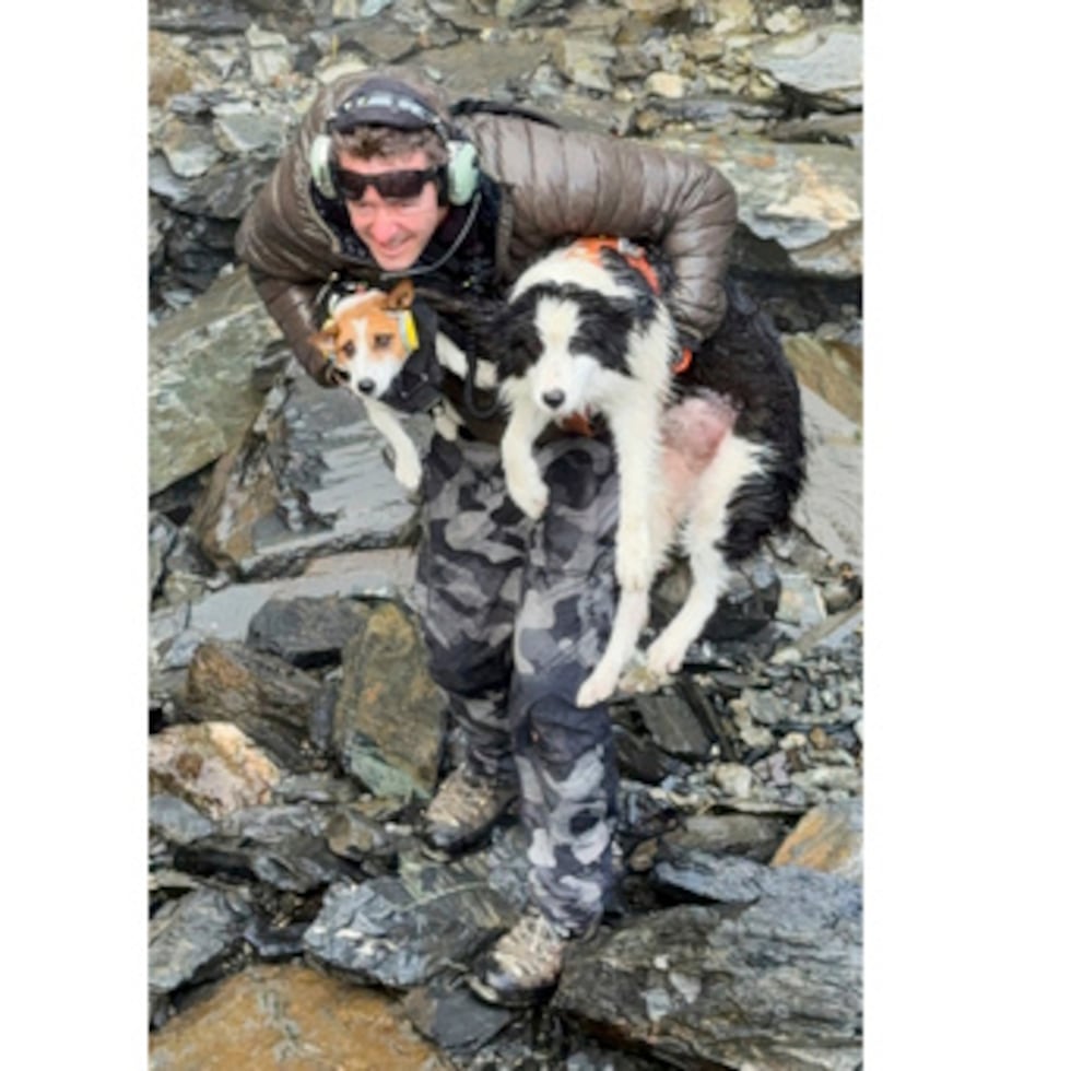 En esta foto difundida por Precision Helicopters Ltd, Wayne Holmes sostiene a su perro Bingo junto a Molly.