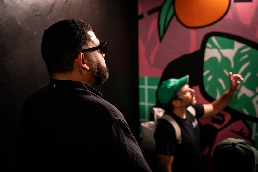 El muralista puertorriqueño Bik Ismo escucha a Adrián Martínez, fundador de la galería en línea Contrabando, durante un recorrido por los murales localizados dentro del edificio Oasis Santurce, de Abarca Health.