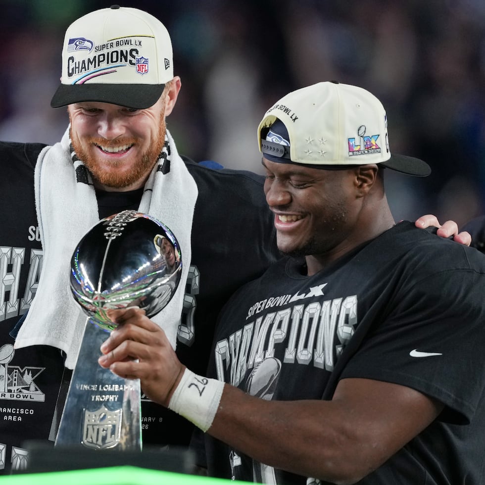 El quarterback Sam Darnold (izquierda) y running back Kenneth Walker III de los Seahawks de Seattle celebran con el Trofeo Lombardi tras la victoria ante los Patriots de Nueva Inglaterra en el Super Bowl.
