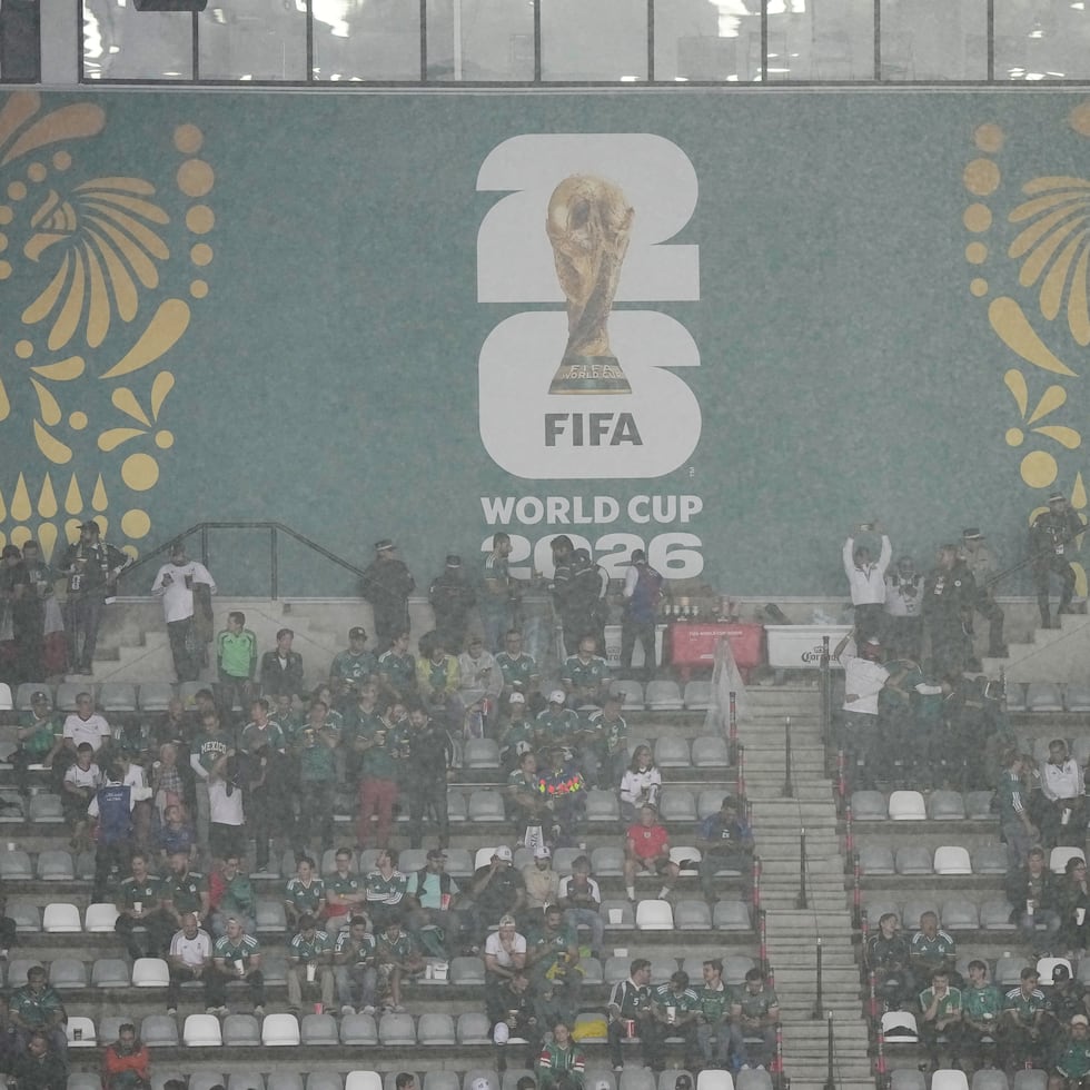Aficionados esperan a que pase la lluvia mientras el partido de octavos de final del Mundial entre México e Inglaterra es retrasado debido a las condiciones del tiempo.