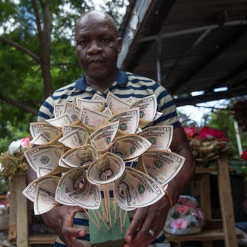 El florista Tongai Mufandaedza sostiene un ramo de dinero diseñado para San Valentín en su puesto de Harare, Zimbabue.