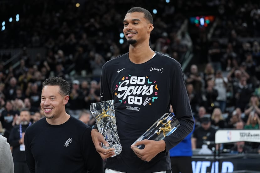 El alero de los Spurs de San Antonio Victor Wembanyama, junto al entrenador Mitch Johnson tras recibir el premio al Defensivo del Año antes del juego 2 de la primera ronda el martes 21 de abril del 2026. (AP Foto/Eric Gay)