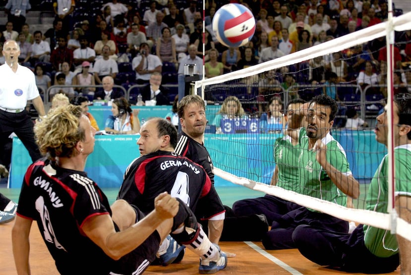 En el voleibol sentado, los jugadores con discapacidades físicas compiten sentados en el suelo, en una cancha más pequeña y con la malla colocada más abajo. Sobre estas líneas, imagen de un partido preliminar de voleibol sentado en los Juegos Paralímpicos de Atenas 2004.