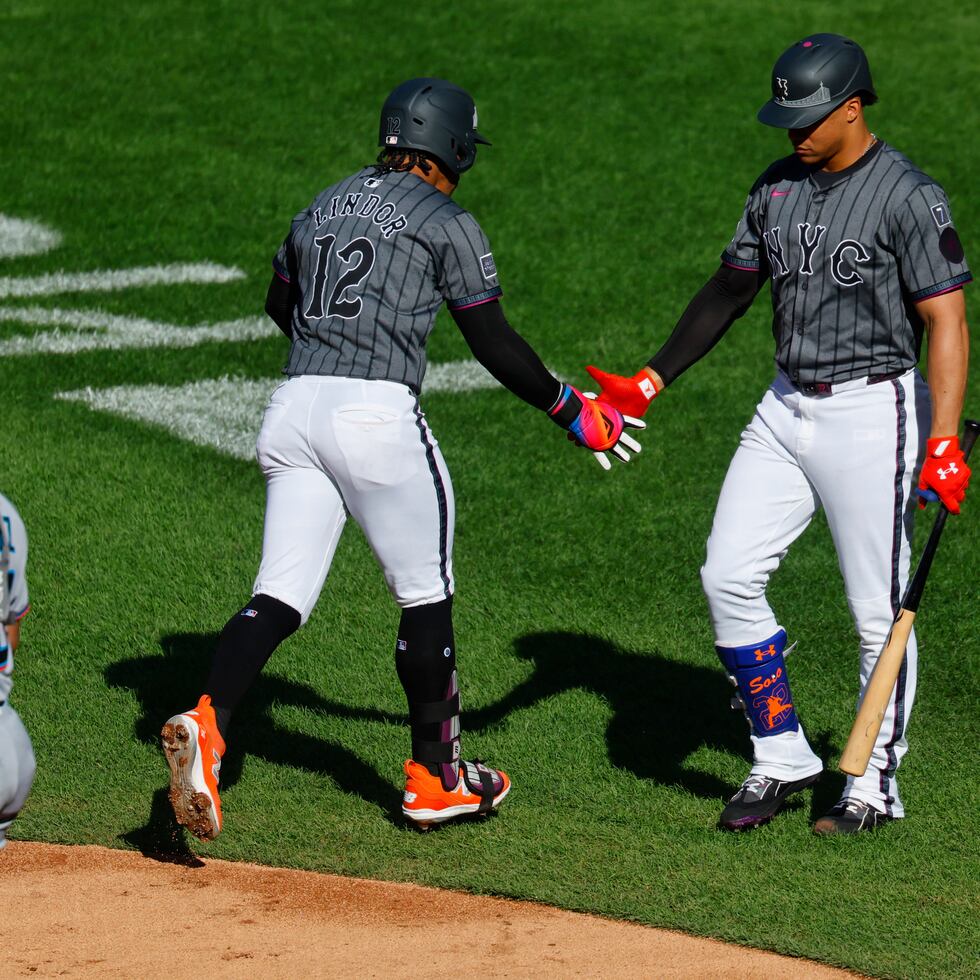 Francisco Lindor (12) choca manos con Juan Soto después de pegar un jonrón solitario en la primera entrada.