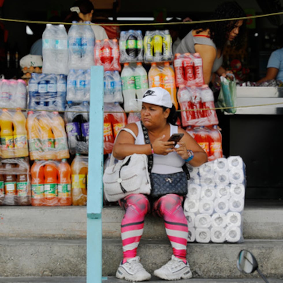 Una mujer sentada frente a una tienda en el barrio de Petare de Caracas, Venezuela.