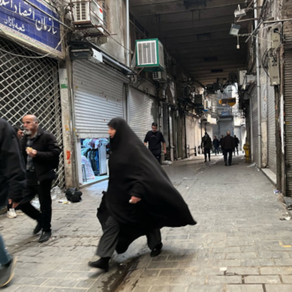 La gente camina mientras las tiendas están cerradas durante las protestas del martes en el centenario bazar principal de Teherán, Irán.