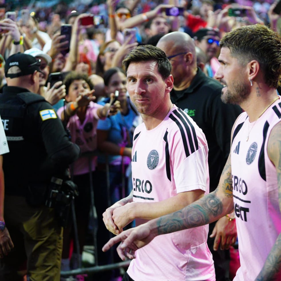 Lionel Messi, acompañado por Rodrigo de Paul, hace su entrada al terreno de juego del Estadio Juan Ramón Loubriel.