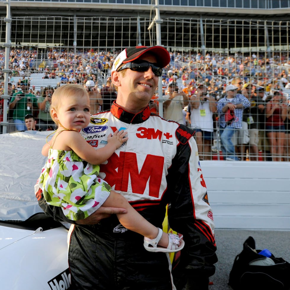 Greg Biffle carga a su hija Emma, ante de la carrera de NASCAR Sprint Cup Series en la pista Atlanta Motor Speedway en 2012.