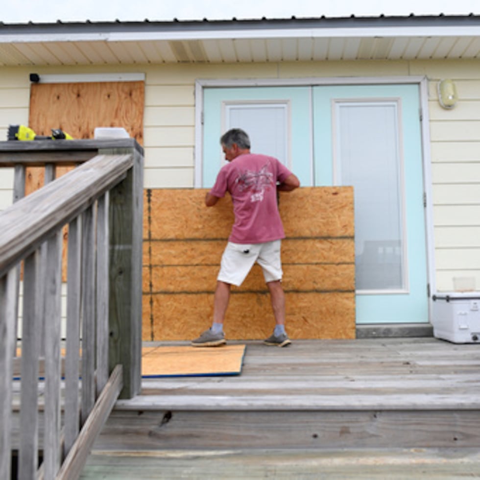 Larry Smith protege su casa con tableros de madera contrachapada ante la llegada prevista del huracán Isaías a la costa del Golfo, en Dauphin Island, Alabama.