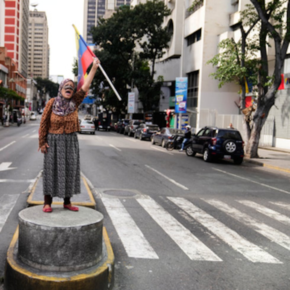 Un simpatizante del presidente venezolano Nicolás Maduro se encuentra en una mediana ondeando una bandera nacional en Caracas, Venezuela, el sábado 3 de enero de 2026, después de que el presidente estadounidense Donald Trump anunció que Maduro fue capturado.