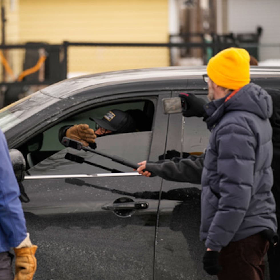 Varios transeúntes graban a un agente federal de inmigración en su coche el domingo, 11 de enero de 2026, en Minneapolis.