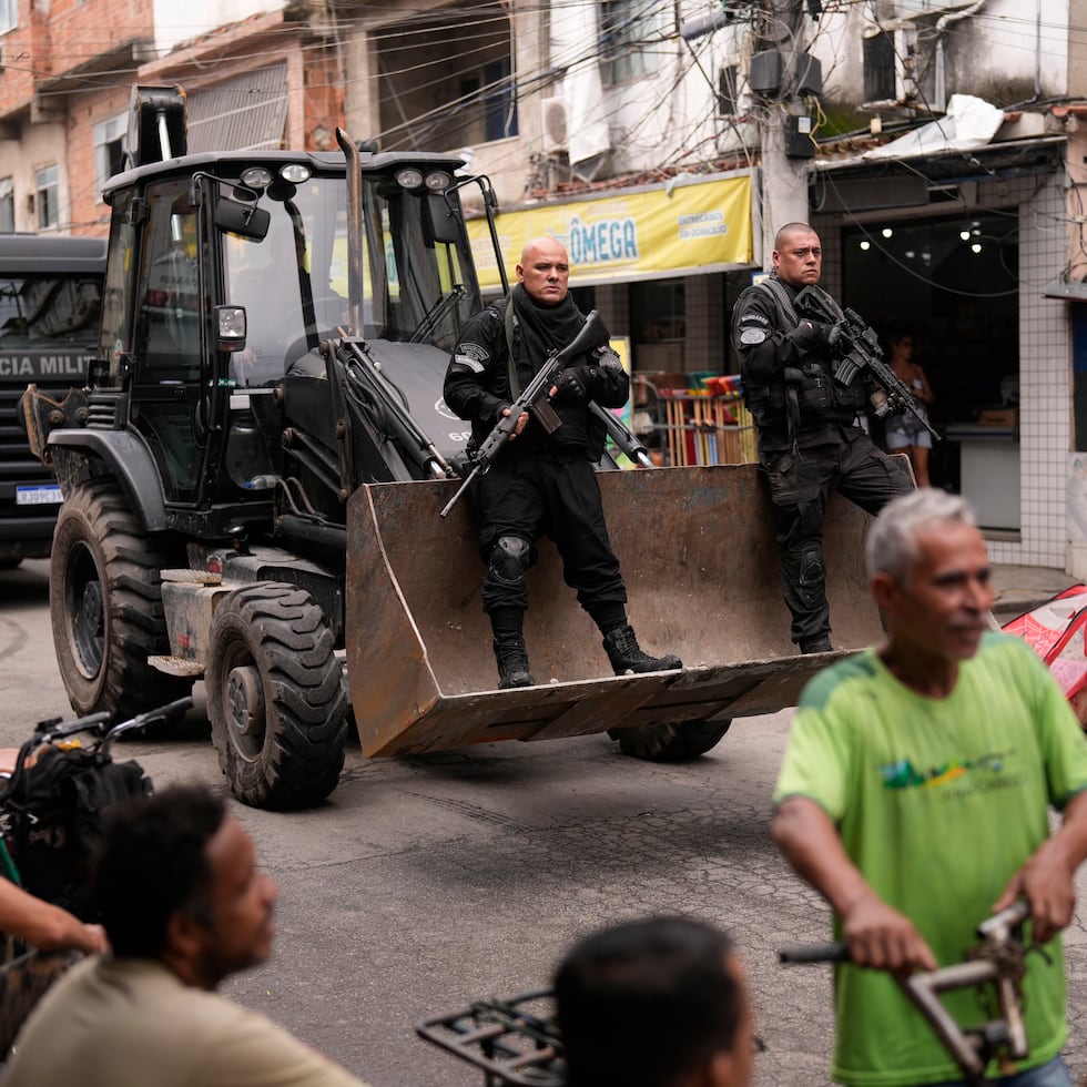 Agentes de policía, patrullan sobre el cazo de una excavadora mientras tratan de retirar las barricadas callejeras durante una operación de seguridad contra el crimen organizado en la favela de Maré, en Río de Janeiro.