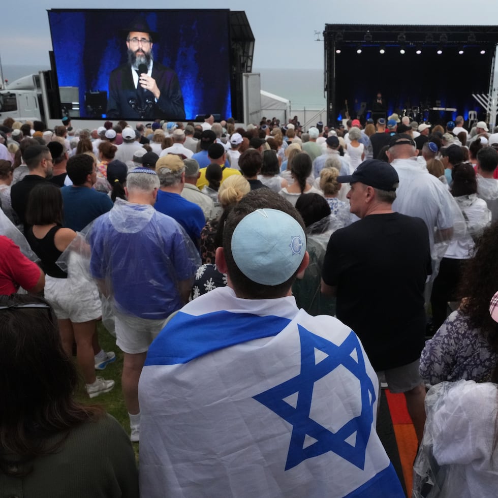 Un grupo de personas asiste a una ceremonia con motivo del Día Nacional de Reflexión por las víctimas y los supervivientes, en la playa de Bondi, en Sídney, el domingo 21 de diciembre de 2025, tras el tiroteo de Bondi del 14 de diciembre (AP Photo/Mark Baker).