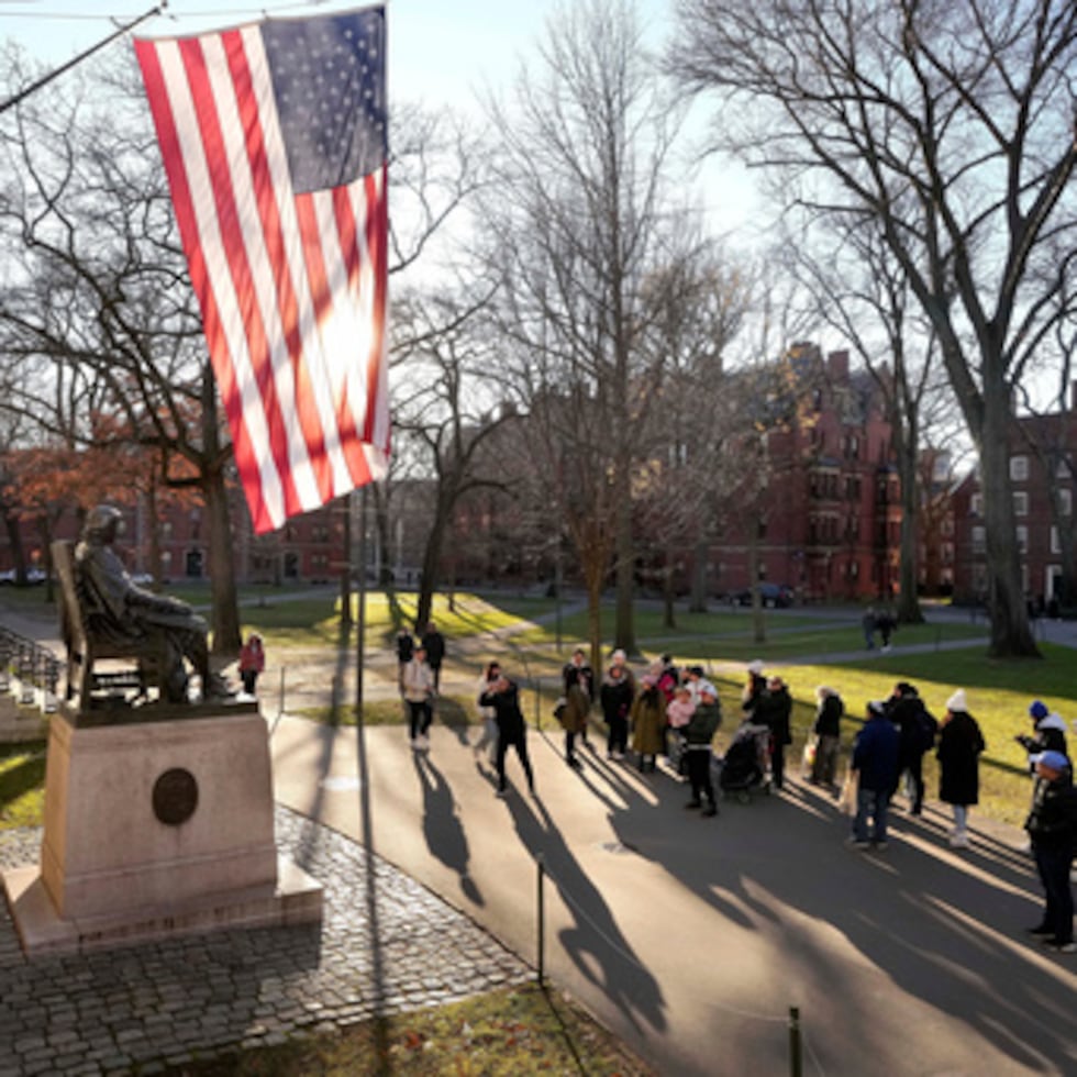 ARCHIVO - La gente toma fotos cerca de una estatua de John Harvard, a la izquierda, en el campus de la Universidad de Harvard, 2 de enero de 2024, en Cambridge, Mass. r. (AP Photo/Steven Senne, File)