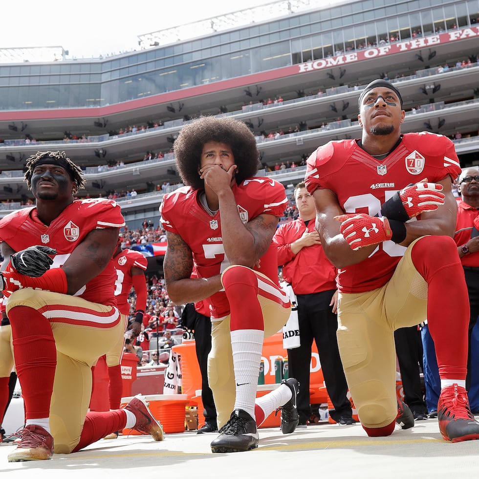 En esta fotografía de archivo del 2 de octubre de 2016, de izquierda a derecha, Eli Harold, Colin Kaepernick y Eric Reid se arrodillan durante el himno nacional antes de un partido de fútbol americano de la NFL contra los Cowboys de Dallas en Santa Clara, California.