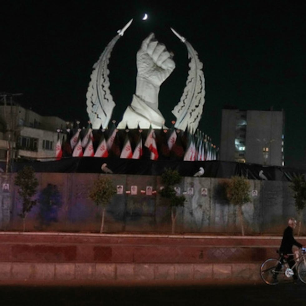 Un hombre lleva su bicicleta frente a un monumento que representa el puño cerrado del difunto líder supremo iraní, el ayatolá Alí Jamenei, quien falleció en el ataque de Estados Unidos e Israel del 28 de febrero, en la Plaza de la Revolución Islámica de Teherán, el domingo 19 de julio de 2026. (Foto AP/Vahid Salemi)