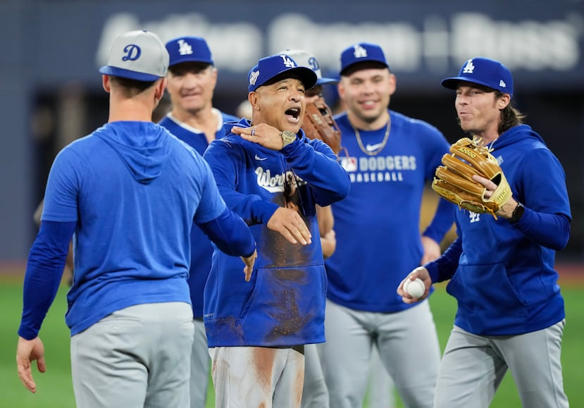 Roberts gesticula mientras los jugadores de los Dodgers parecen embromarlo por su caída.