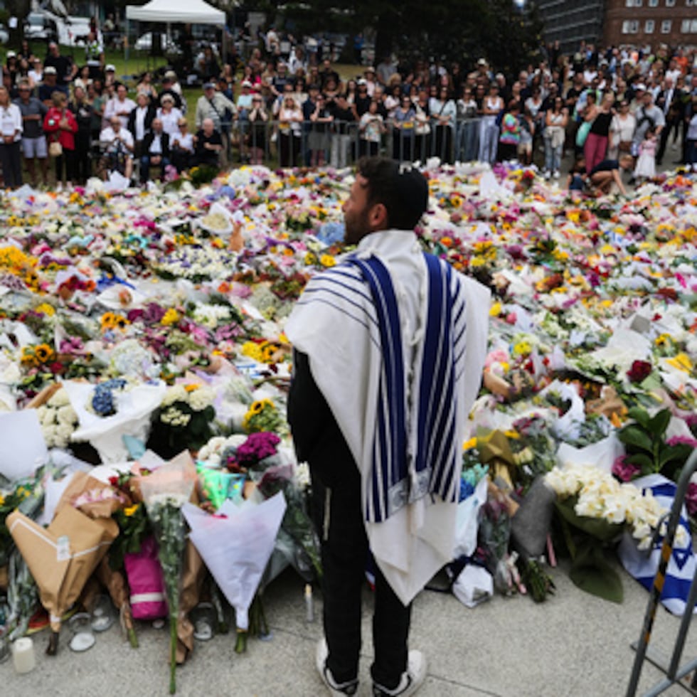 El rabino Yossi Friedman habla con gente reunida en un altar improvisado junto al Bondi Pavilion en el distrito de Bondi Beach, el martes tras el tiroteo del domingo en Sydney, Australia.