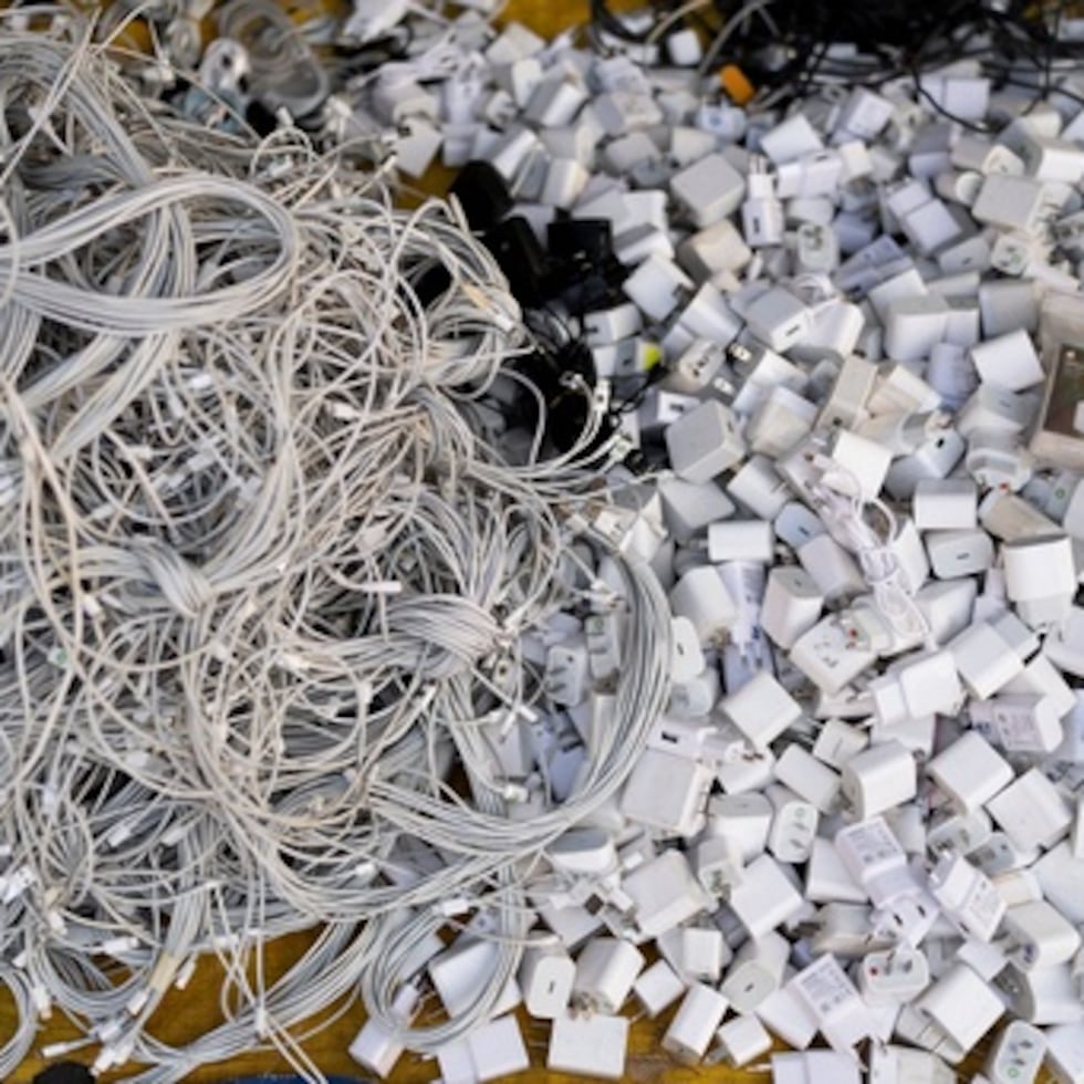 Cables de carga y adaptadores de corriente usados se apilan en una tienda del mercado de Nhat Tao.
