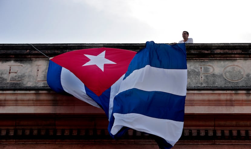 Un joven coloca una bandera cubana en el techo de una de las facultades de la Universidad de La Habana, donde estudiantes participaron en un acto para ver en una pantalla el discurso del canciller cubano Bruno Rodríguez en la ONU.