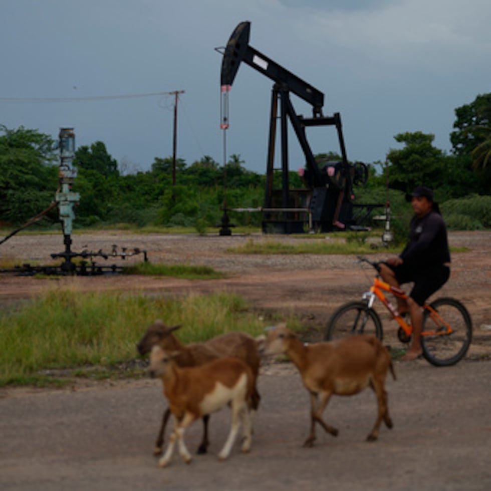 Un hombre pasa en bicicleta junto a una bomba de petróleo en funcionamiento en Cabimas, Venezuela.