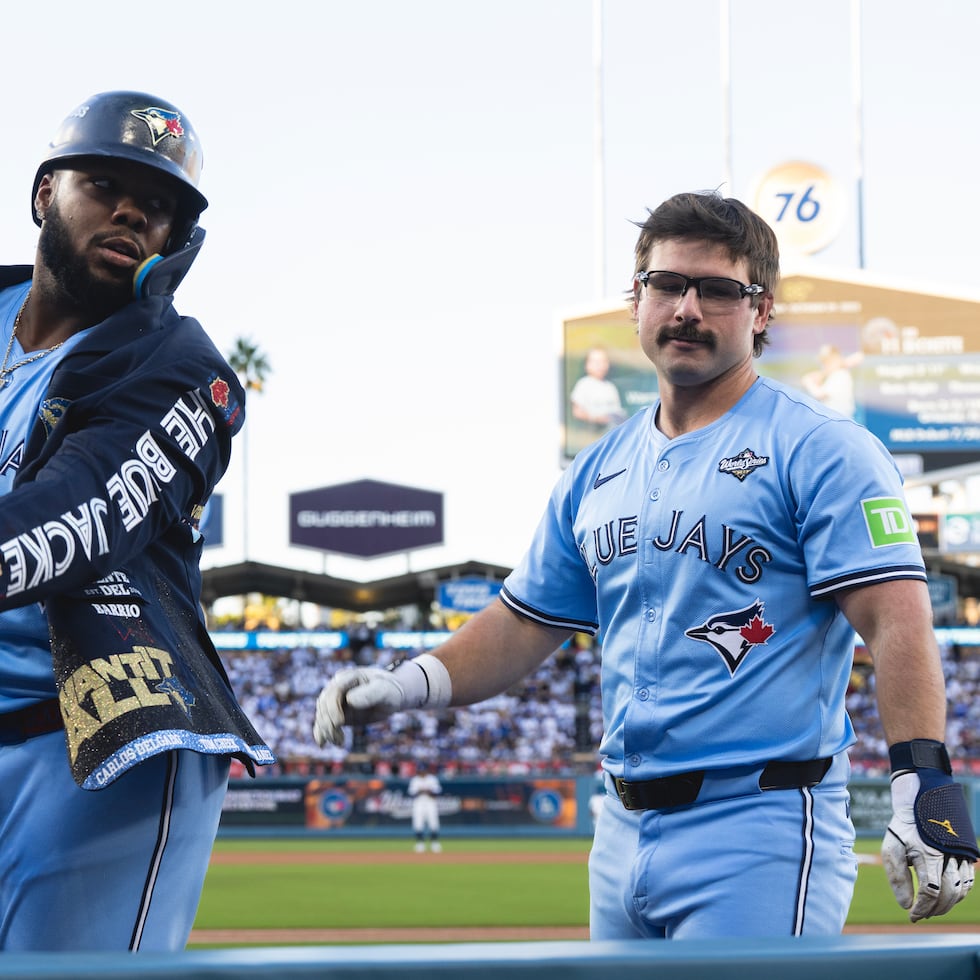 El dominicano Vladimir Guerrero Jr. festeja con Davis Schneider, su compañero en los Blue Jays de Toronto, después de conseguir un jonrón en el quinto juego de la Serie Mundial ante los Dodgers de Los Ángeles, el miércoles 29 de octubre de 2025 (Frank Gunn/The Canadian Press via AP)