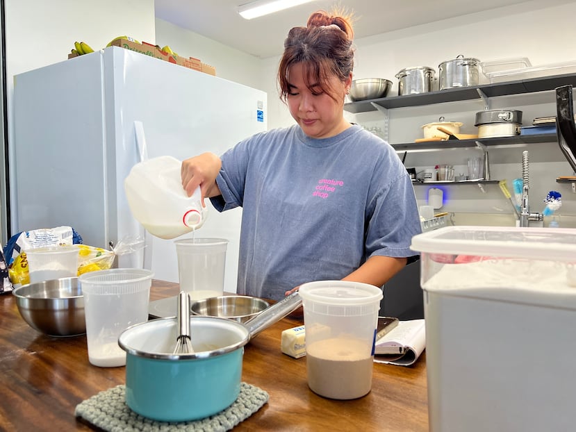 La pastelera Amanda Tabadero vierte leche en un recipiente de plástico mientras prepara los ingredientes para los maritozzi en la cafetería Creature Coffeeshop en Kaneʻohe, Hawái, el martes 7 de julio de 2026. (Hikari Mae Hida/Honolulu Civil Beat vía AP)