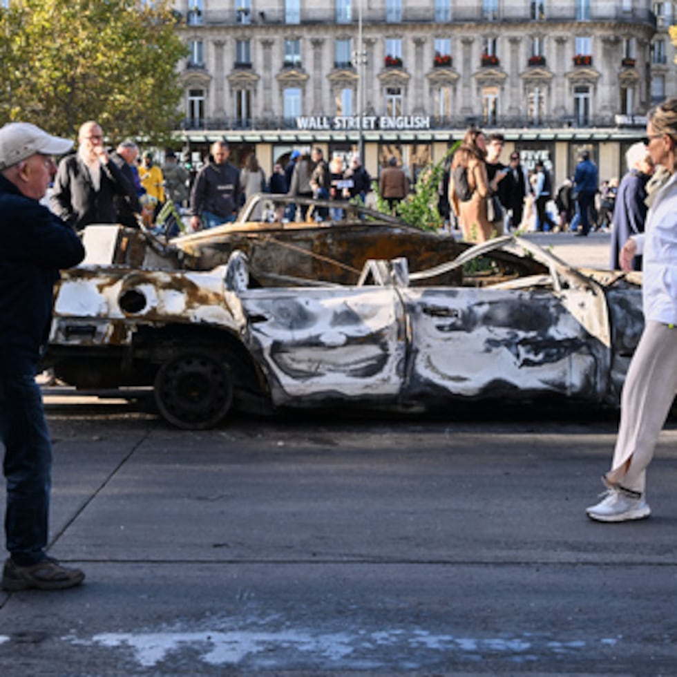 Varias personas observan un coche calcinado en la Place de la République tras las protestas.