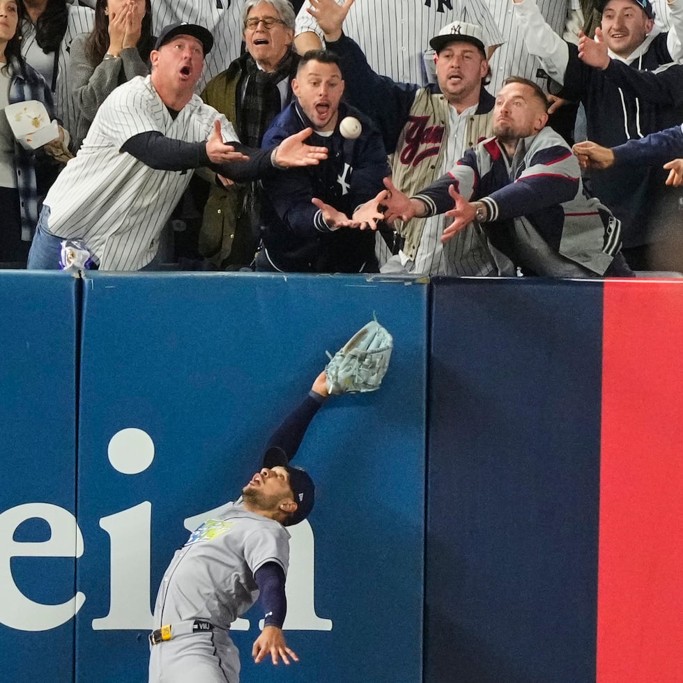 El jardinero izquierdo Víctor Mesa Jr. de los Rays de Tampa Bay trata de atrapar una pelota interferida por fanáticos tras el batazo de Anthony Volpe de los Yankees de Nueva York, en el sexto inning del tercer juego de la serie divisional de la Liga Americana, el miércoles 7 de octubre de 2026, en Nueva York. (AP Foto/Yuki Iwamura)